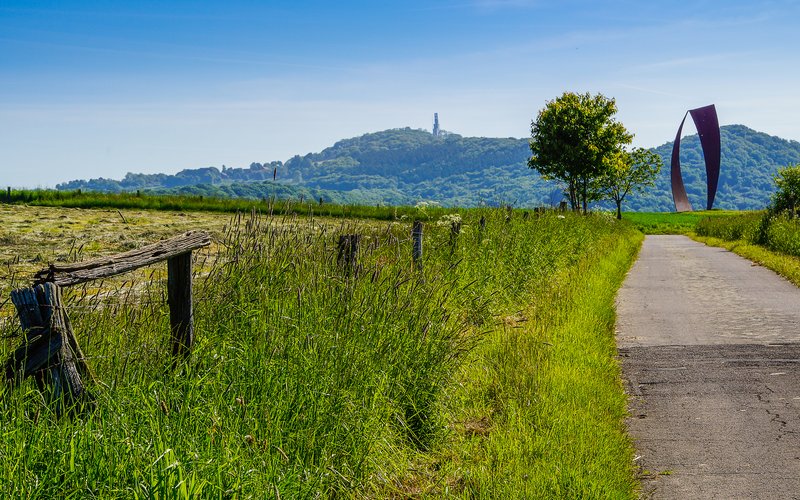 Weg entlang der Wortsegel-Skulptur, der Schaumberg im Hintergrund