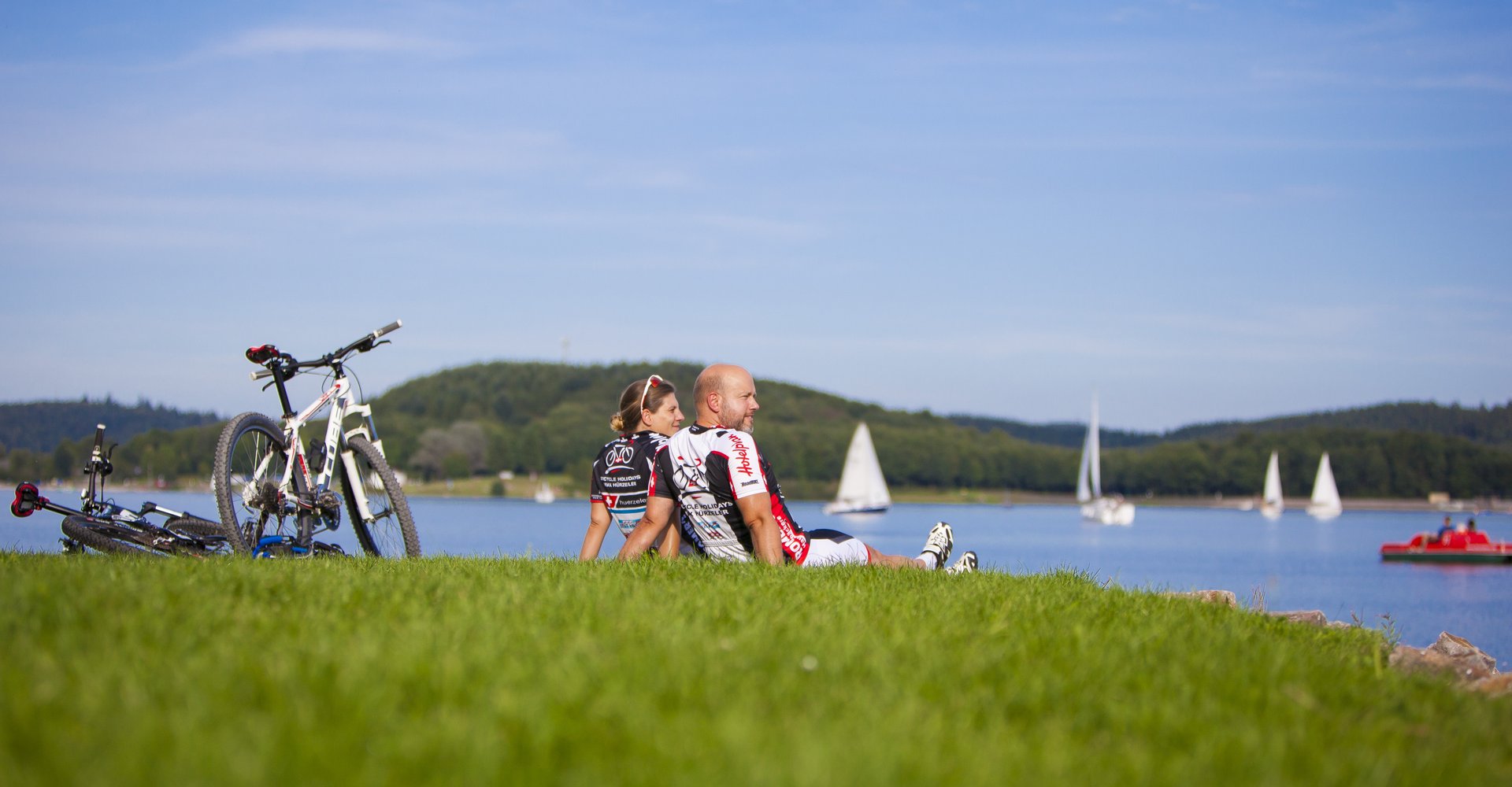 Zwei Fahrradfahrer sitzen auf einer Wiese am Bostalsee