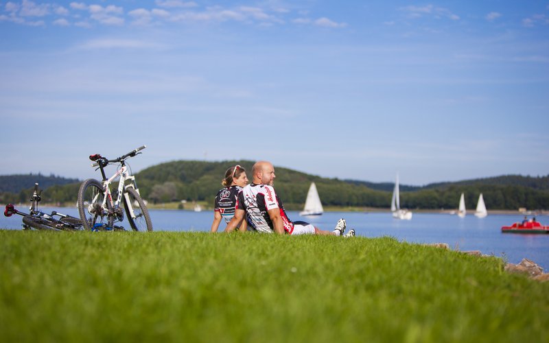 Zwei Fahrradfahrer sitzen auf einer Wiese am Bostalsee