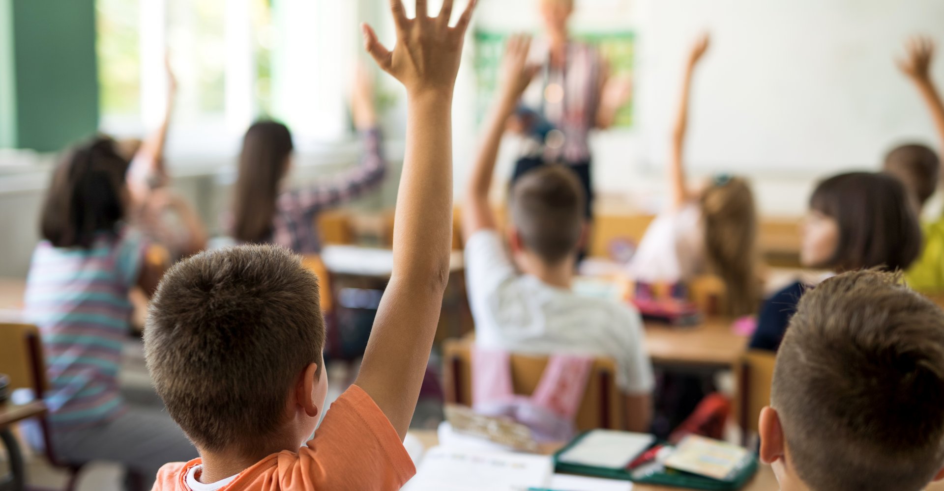 Kinder im Klassenraum, die sich melden.